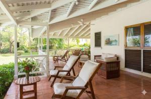 a covered porch with chairs and a table at The Rocks Villa in Tower Isle
