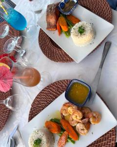 two plates of food on a table with shrimp and vegetables at The Rocks Villa in Tower Isle +15 photos