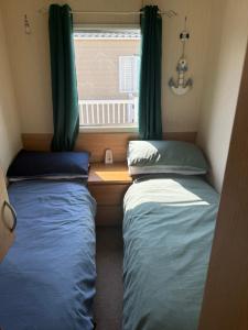 two beds in a small room with a window at Holiday Caravan Orchards Holiday Village in Brightlingsea