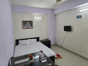 a bedroom with a bed and a table and a tv at Epindi Studio Apartment in Cox's Bazar