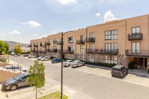 an apartment building with cars parked in a parking lot at Oasis privado en Querétaro in Alvarado