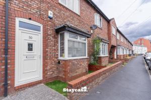 a brick house with a white door on a street at Spacious 2BR Home w Garden 2-Min Walk to Town in Stockport