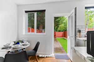 a white kitchen and dining room with a table and chairs at Spacious 2BR Home w Garden 2-Min Walk to Town in Stockport