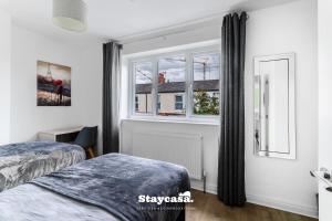 a bedroom with two beds and a window at Spacious 2BR Home w Garden 2-Min Walk to Town in Stockport