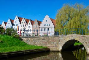 a bridge over a river in front of a large building at Friesen-Cottage in Friedrichstadt
