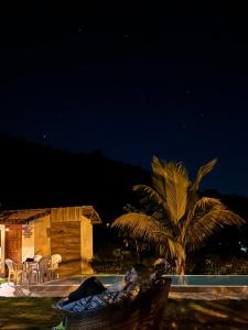 a woman laying in a hammock by a pool at night at Casa na Serra Canto do Jair in Casimiro de Abreu