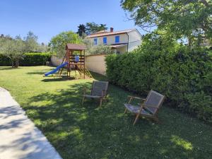 two chairs and a playground in a yard at Villa Tramonto 4 stars, Krnica in Krnica