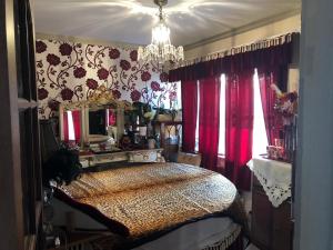 a bedroom with a bed with red curtains and a chandelier at Bonnye's guest house in Ramsgate
