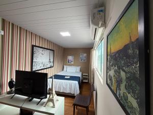 a bedroom with a bed and a desk with a tv at Pousada Beach House Coqueirinho in Jacumã +180 photos