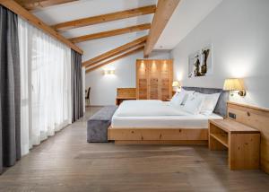 a bedroom with a large bed and a table at Hotel Chalet Dlaces in Selva di Val Gardena