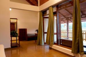 a living room with a large window and a bedroom at HighFields Coorg in Virajpet