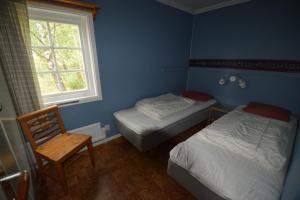 a bedroom with two beds and a chair and a window at Ekesberget Stugby stuga 6 in Ekshärad