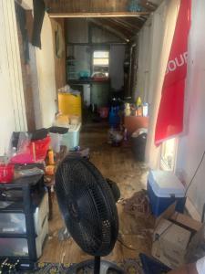 a messy living room with a fan in it at Good home in Codrington Village