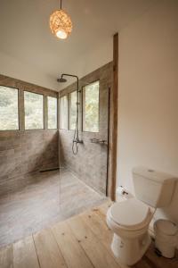 a bathroom with a toilet and a glass shower at Ahora Wellness Hostel in Guachaca +15 photos