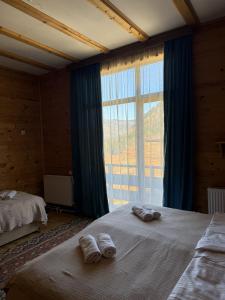 a bedroom with two towels on a bed with a large window at Panorama Gomarduli in Shuakhevi