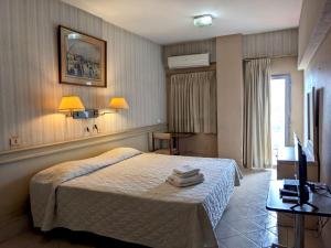 a bedroom with a bed and a desk and a television at Hotel Armele Asunción in Asunción