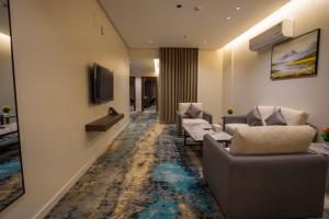 a living room with couches and a tv on a wall at iqama mumayyaza الإقامة المميزة للشقق المخدومة - إقتصادي in Tabuk