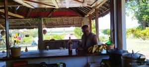 a man standing at a bar with a bunch of bananas at Caban Zenfants in Sainte Marie