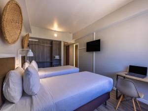 a hotel room with two beds and a desk with a laptop at B&B HOTEL Rio Copacabana Posto 5 in Rio de Janeiro