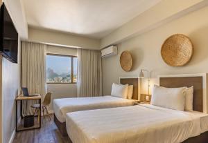 a hotel room with two beds and a window at B&B HOTEL Rio Copacabana Posto 5 in Rio de Janeiro +30 photos