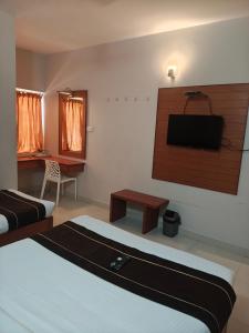 a room with two beds and a television on the wall at skylink residency in Chennai
