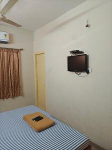 a bedroom with a bed and a tv on the wall at skylink residency in Chennai