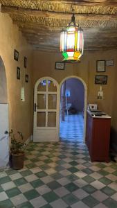 a room with a chandelier and a checkerboard floor at Tigmi Hamid Découverte des traditions et de la culture berbère in Aït Benhaddou