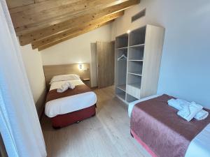 two beds in a small room with wooden ceilings at Apartamentos Los 5 Sentidos in Grado
