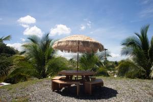 a picnic table with a straw umbrella and a bench at La Ceiba Suite 2 with private plunge pool in Anasco