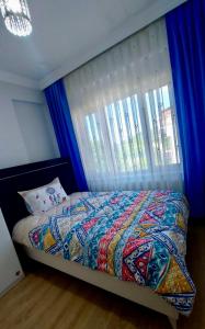 a bedroom with a bed with blue curtains and a window at Seafront Apartment Rize - Ardeşen in Ardeşen