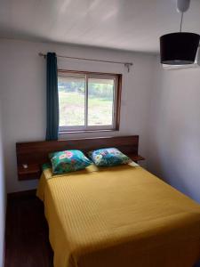 a bedroom with a yellow bed with a window at Le coin des Maripas in Quesnel