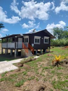 a black house with a porch and a yard at Le coin des Maripas in Quesnel