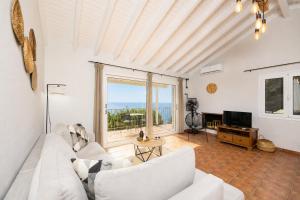 a living room with a white couch and a television at Villa Gardenia in Vlachopoulátika