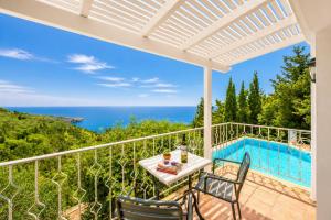 a balcony with a table and chairs and a swimming pool at Villa Gardenia in Vlachopoulátika