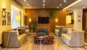 a living room with couches and a tv and a table at Adana Plaza Hotel in Adana