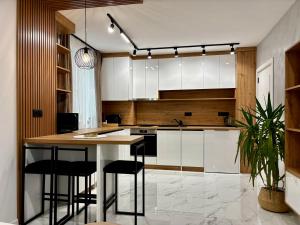 a kitchen with white cabinets and a island with bar stools at Arena Apartment in Gotse Delchev