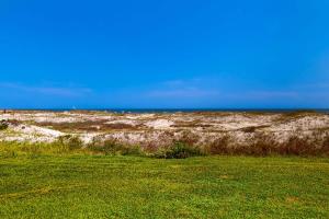 a field of grass with the ocean in the background at #1131 The Mermaid Pad in Gulf Highlands