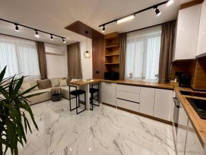 a kitchen with white cabinets and a table with chairs at Arena Apartment in Gotse Delchev