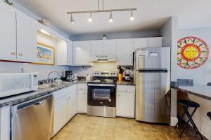 a kitchen with white cabinets and stainless steel appliances at Plantation East #1110 in Gulf Shores +56 photos