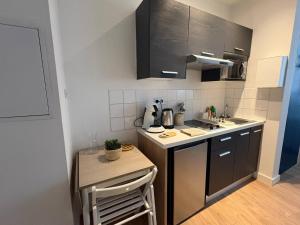 a small kitchen with black cabinets and a small table at Coudert l Petit studio côté rue l Rez-de-chaussée en Hypercentre & climatisé in Castres