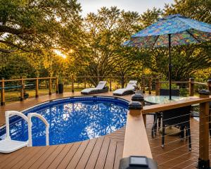 a pool with a table and an umbrella on a deck at Serene Mountain Retreat With Pool in Clermont