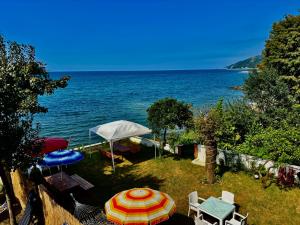 a garden with an umbrella and chairs and the ocean at Seafront Apartment Rize - Ardeşen in Ardeşen