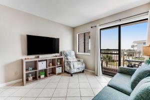a living room with a tv and a couch and a chair at Condo by the beach with Gulf views plus shared pool in Fort Morgan