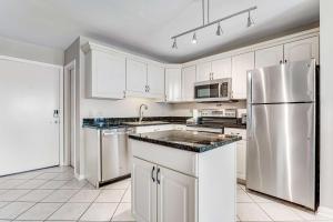 a kitchen with white cabinets and a stainless steel refrigerator at Condo by the beach with Gulf views plus shared pool in Fort Morgan
