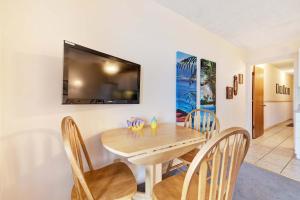 a dining room with a table and chairs and a television at Waterfront Gulf condo with beach access shared pool in Fort Morgan
