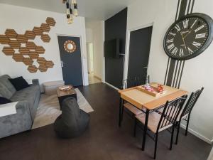 ein Wohnzimmer mit einem Tisch und einer Uhr an der Wand in der Unterkunft Le Maley in Dunkerque