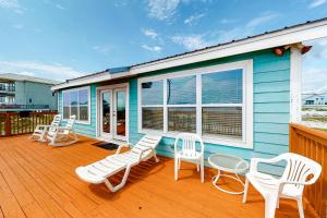 a blue house with white chairs and a deck at Fine Fish House in Gulf Highlands