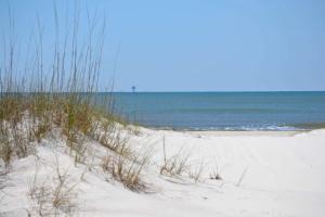 a beach with grass and the ocean in the background at Gulf view duplex with multi-level balcony hot tub in Fort Morgan