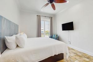 a white bedroom with a bed and a ceiling fan at Beachfront dog-friendly home with private pool sundeck and elevator in Fort Morgan
