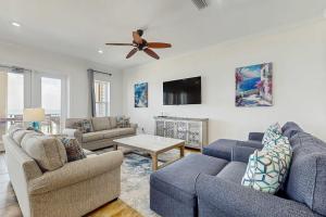 a living room with two blue couches and a ceiling fan at Beachfront dog-friendly home with private pool sundeck and elevator in Fort Morgan